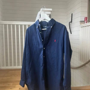 Mörkblå skjorta från Ralph Lauren - Mycket fin skjorta i storleken S men passar även M. Bomull 100%. Skick 9/10 knappt aldrig använt den. Pris kan diskuteras vid snabba frågor. Skriv om du har några fler frågor.