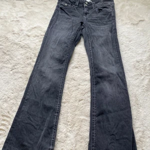 Svarta bootcut jeans från Gina Tricot - Snygga svarta jeans från Gina Tricot i storlek 164. Modellen har bootcut-ben och klassisk femficksdesign. Jeansen är tillverkade i ett mjukt denimtyg med vita kontrastsömmar och stängs med knapp och dragkedja.