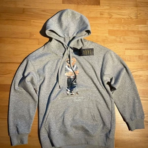 Grå hoodie Polo Bear från Ralph Lauren - Snygg grå hoodie från Polo Ralph Lauren med ikoniska Polo Bear-trycket på bröstet. Tröjan har huva med snörning. Tröjan är inte äkta! Medium men passar small.