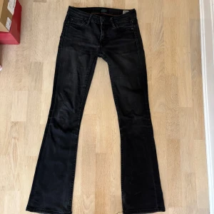 Svarta bootcut jeans från Crocker - Snygga svarta jeans från Crocker med bootcut-modell och klassisk femficksdesign. Jeansen har en mörk tvätt och subtila slitningar för en cool look. Tillverkade i jeansmaterial med detaljerade sömmar och läderpatch bak i midjan. Storlek 26/31!🩷