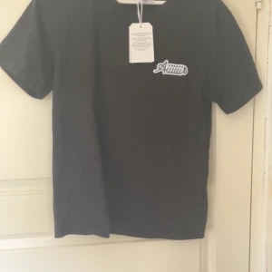 Svart Casablanca t-shirt med tryck - Svart t-shirt från Casablanca med stort färgglatt tryck på ryggen med flygplansmotiv och texten 'Aiiiir'. Framsidan har en mindre logga. Klassisk passform och rund hals. Tillverkad i mjuk bomull, perfekt för en chill och stilren look.