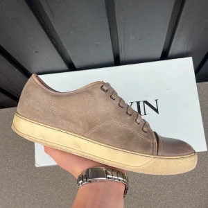 Grå/Beige lanvin DBB1 - Säljer ett par sköna beige och grå lanvins i uk7 🔥 (box ingår inte). Skick avgör ni själva, enda stora defekten är captoen (se bilder). Insidan har som på bild lossnat, men går enkelt att laga med laglapp. Hör av er vid frågor eller funderingar 🙏 Öppen för byten 👀