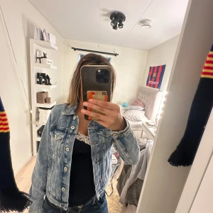 Ljusblå jeansjacka med knappar - Säljer en klassisk ljusblå jeansjacka med snygga silvriga knappar framtill. Jackan har en rak passform, två bröstfickor med lock och långa ärmar. Perfekt att slänga över en hoodie eller t-shirt för en chill look.