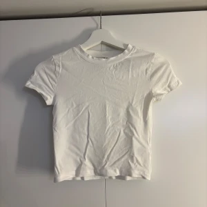 Vit basic t-shirt i bomull - En klassisk vit t-shirt med rund hals och korta ärmar som är lite croppad. Från H&M