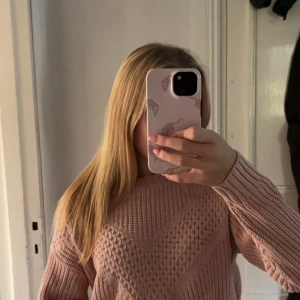 Ljusrosa stickad tröja med mönster - Superfin ljusrosa stickad tröja med snyggt strukturmönster framtill. Tröjan har långärmad modell och ribbade muddar vid ärmslut och nederkant. Perfekt för dig som vill ha en mysig och trendig look!