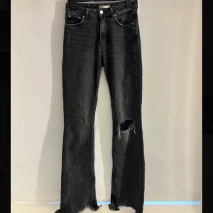 Svarta Jeans - Svarta jeans från Gina med snyggt sliten look och hål på ena benet. Sitter perfekt på mig som är 168cm. De är mid waist. Säljer pg de är försmå. Annars bra kvalitet.