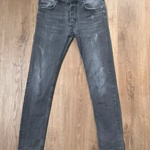 Dsquared2 Jeans - Snygga grå jeans från Dsquared2 ICON med slitna detaljer och smal passform. Klassisk femficksmodell, grönt Dsquared2-märke bak och diskret logga vid gylfen. Jeansen är i stretchigt denim och har en modern, urban vibe.