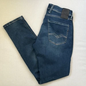 Replay Hyperflex Anbass jeans blå - Snygga blå Replay Hyperflex Anbass jeans med klassisk femficksdesign och coola kontrastsömmar på bakfickan. Jeansen är i stretchigt denim som ger en skön passform och har en modern look med medelhög midja.