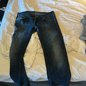 Mörkblå jeans från Lee - Säljer ett par klassiska mörkblå jeans från Lee med snygg tvätt och raka ben. Jeansen har fem fickor, knappgylf och Lee-logga på bakfickan. Perfekta för dig som gillar en tidlös och avslappnad stil. Storlek 32:30