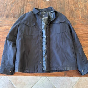 Mörkblå dunjacka från Massimo Dutti M - Stilren mörkblå dunjacka från Massimo Dutti med quiltat foder och tryckknappar. Jackan har två bröstfickor med lock och klassisk krage. Perfekt för lager-på-lager och snygg till både jeans och chinos.