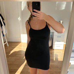 Svart miniklänning  - Svart miniklänning med smala axelband och tight passform i superskönt material. Klänningen är kort men går att välja om man vill ha den mini eller lite längre. Aldrig använd, storlek 36/s. 