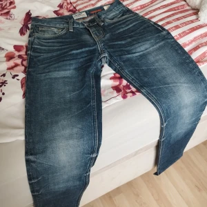 Blå slim fit jeans från Crocker - Snygga blå jeans från Crocker i modellen 310 Slim. Jeansen har klassisk femficksdesign, orange sömmar och slitningar för en cool look. Tillverkade i bekvämt denimtyg som sitter tajt men ändå är sköna att bära.
