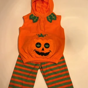Randiga pumpabyxor i orange och grönt - Säljer ett par färgglada byxor med orange och gröna ränder, perfekta för halloween eller maskerad. Byxorna har resår i midjan och är tillverkade i mjukt bomullstyg. Matchar pumpatoppen med huva och broderat ansikte.