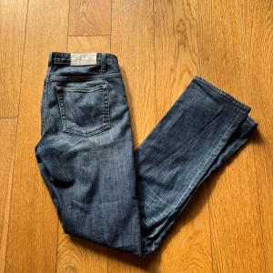 Acne Jeans blå raka jeans - Snygga blå jeans från Acne Jeans. Jeansen har en mörk tvätt med lätt slitning och normal passform. Tillverkade i mjukt jeanstyg med dragkedja och knapp framtill. Perfekta för en stilren och avslappnad look. 30W 34L