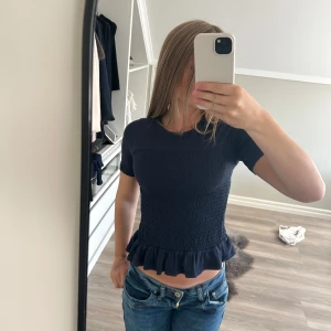 Marinblå topp - Supersöt svart topp från Gina Tricot med volangkant nertill. Toppen har korta ärmar och rund halsringning. Använd hyfsat många gånger men är i bra skick. Den är i storlek 146-152.❤️