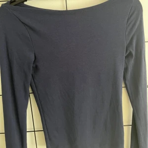 Mörkblå långärmad topp Gina Tricot - En stilren mörkblå långärmad topp från Gina Tricot. Toppen har en enkel, tight passform och är tillverkad i mjuk bomullsmix. Perfekt att matcha med jeans eller kjol för en clean look.