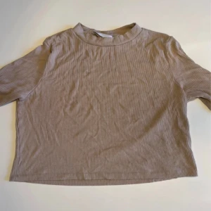 Beige ribbad croppad tröja - Säljer en beige ribbad croppad långärmad tröja från Lager157. Tröjan har en rak passform, diskret ståkrage och är tillverkad i ett mjukt, stretchigt material. 