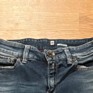 Blå skinny jeans från Replay, stl 26 - Snygga blå skinny jeans från Replay i klassisk tvätt med slitningar och detaljerade bakfickor. Jeansen har normal midja, smal passform och är tillverkade i stretchigt denim för en bekväm känsla. Perfekta för dig som gillar en tajt look.