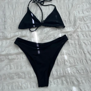 Svart bikini med knyt och trekantsform - Snygg svart bikini med klassisk trekantsform på överdelen och knyt i nacken och ryggen. Underdelen har en medelhög midja och enkel design. Överdelen är från shein i storlek S och underdelen är från h&m i storlek XS