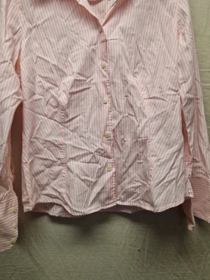 Rosa- och vitrandig skjorta Stenströms - Säljer en klassisk rosa- och vitrandig skjorta från Stenströms i storlek 38. Skjortan har långa ärmar, knappar framtill och är gjord i mjuk bomull. Perfekt för en clean och fräsch look med tidlös känsla.