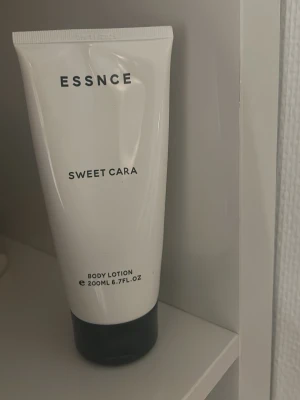 ESSNCE Sweet Cara Body Lotion  - Body lotion från ESSNCE i doften Sweet Cara. Innehåller noter av kokos, pistage, jasmin och vanilj. Kommer i en vit tub med svart lock och rymmer 200 ml. Ca 70% kvar