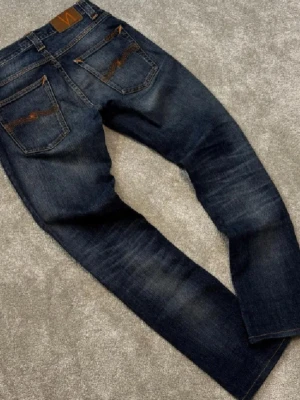 Mörkblåa Nudie jeans - Snygga  mörkblå Nudie jeans med fin wash. Topp skick, knappt använda. Slim/straight passform, slitstarkt och bekvämt material. Perfekta för vardag eller fest.