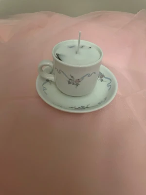 Doftljus av vaniljdoft i en vit tekopp med blommor och blåa streck nr 3 - Det här ljuset är gjort av återanvändbara material. Tekoppen är köpt secondhand och stearinet är från kyrkor som tänkte slänga det. Det här ljuset har en svag doft utav vanilj, så känsliga även kan använda det. Det här ljuset har även torkade blommor på som dekoration. Det finns fler av denna design på hemsidan om man vill köpa sets. 