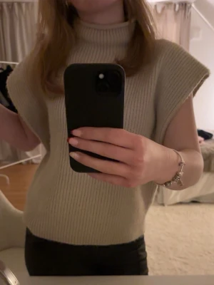 Beige stickad polotröja ärmlös - Skickar samma dag💕💕 Säljer en beige stickad polotröja utan ärmar. Tröjan har ribbad struktur och hög krage som ger en clean och trendig look. Perfekt att styla med skjorta under eller som den är för en chill vibe.