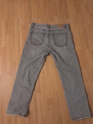 Grå  jeans från Zara - Säljer ett par grå jeans från Zara. Jeansen har råa kanter vid bensluten för en avslappnad vibe. Perfekta till sneakers eller boots. Gick sönder lite mellan benen men den är sydd. 
