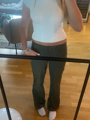 Olivgröna utsvängda mid/lowaist byxor  - Säljer ett par olivgröna cargopants med raka ben och fickor på sidorna. Byxorna har hög midja, bälteshällor och stängs med dragkedja och knapp. Perfekta för en chill och avslappnad stil. Pyttelite korta på mig som är 170cm men annars snygga. 