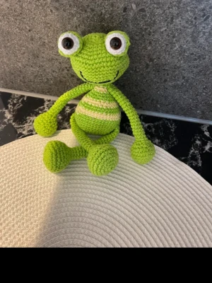 Grön stickad väst med ränder - Säljer en grön stickad väst med ljusa ränder. Västen har en klassisk, rundad form och är gjord i ett mjukt, virkat material. Perfekt för dig som vill ha en unik och färgglad detalj i garderoben.