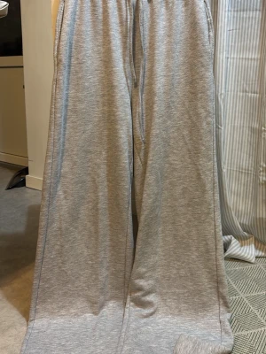 Grå wide mjukisbyxor med snörning - Säljer ett par grå mjukisbyxor, utsvängda needtill och snörning i midjan. Väldigt långa i benen av den anledning säljer jag dem då dem inte passar mig, använt dem 2 gånger max. 