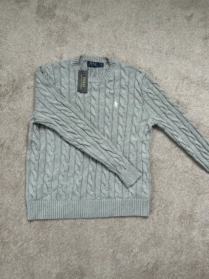 Ralph Lauren Tröja - Grå stickad tröja från Polo Ralph Lauren i storlek M. Klassisk och skitsnygg. Passar till allt. Helt ny, och oanvänd. 