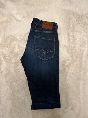 Mörkblå Replay Anbass jeans slim fit - Säljer ett par Replay Anbass jeans i mörkblå denim med slim fit-passform. Jeansen är i nyskick och knappt använda, utan slitningar, fläckar eller andra defekter. Klassisk Replay-design som funkar lika bra till vardags som till en mer uppklädd stil. Storlek W29/L32. Öppen för seriösa bud. Hör av dig vid funderingar! MVH PolarArchive 