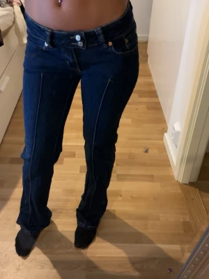 Mörkblå bootcut jeans med söm - Säljer ett par lågmidjade mörkblå jeans med bootcut-modell och markerade sömmar framtill i stolek xs