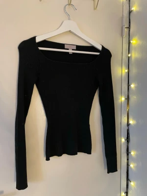 Svart ribbad tröja från H&M - Säljer en svart, ribbad långärmad tröja från H&M i storlek XS. Tröjan har en snygg, fyrkantig urringning och sitter tight mot kroppen🤩