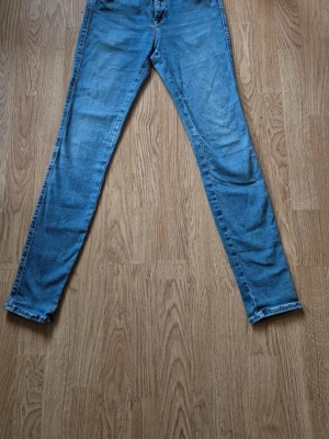 Replay blå skinny jeans - Säljer ett par blå skinny jeans från Replay med klassisk femficksdesign och snygga detaljer som Replay-logga på bakfickan och läderpatch i midjan. Jeansen har smal passform och är tillverkade i mjukt jeansmaterial med lite stretch för extra komfort.