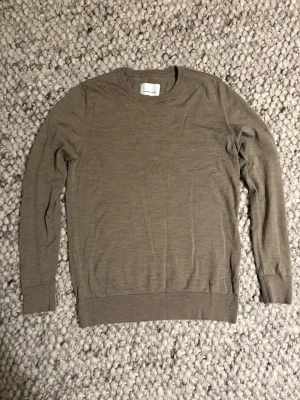Beige stickadtröja i merinoull från Samsøe Samsøe - Snygg beige långärmad stickadtröja i merinoull från Samsøe Samsøe i storlek M. Tröjan har en rund halsringning och är tillverkad i ett mjukt och tunt material som passar perfekt för lager-på-lager. Enkel och stilren design som funkar till många olika outfits.