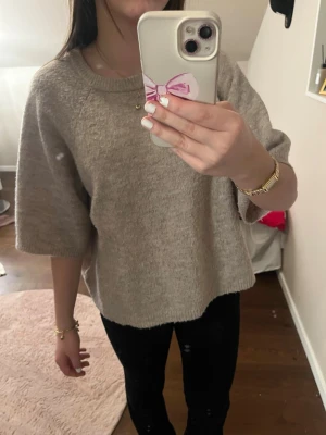 Beige stickad tröja/t-shirt - Supermjuk stickad tröja i beige med breda, trekvartsärmar och rund hals. Perfekt att slänga på sig för en chill och stilren look. Passar lika bra till jeans som till kjol. Enkel och clean design utan mönster eller detaljer.