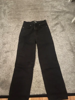 Svarta jeans från Madlady - Säljer ett par svarta jeans från Madlady i storlek 36. Klassisk femficksmodell och stängs med dragkedja och knapp. Materialet är slitstarkt jeans och färgen är helt svart.
