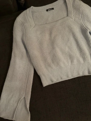 Ljusblå stickad tröja Gina Tricot - Superfin ljusblå stickad tröja från Gina Tricot med fyrkantig ringning och långa ärmar. Tröjan är ribbstickad och har en croppad passform. Storlek small