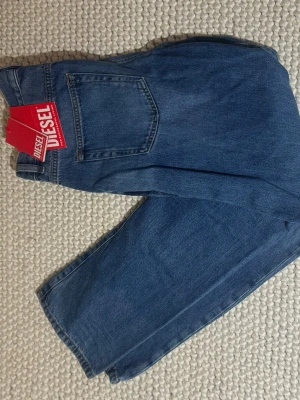 Blåa straightfit jeans från Diesel - Säljer ett par klassiska blå jeans från Diesel med raka ben och normal passform. Jeansen har en enkel bakficka och tydliga sömmar. Perfekta för dig som gillar tidlös denimstil.  Helt oanvänd med prislappar kvar nypris ca 2300+