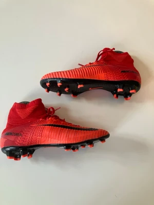 Nike Mercurial röda fotbollsskor elite - Säljer ett par Nike Mercurial fotbollsskor elite med strumpkrage för extra stöd runt ankeln och för bättre bollkontroll. 