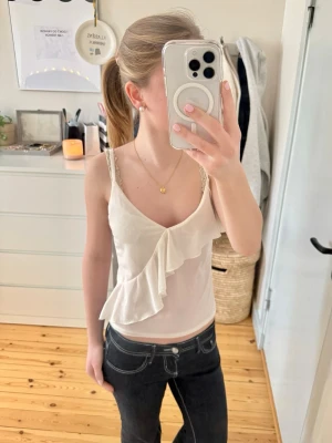Vit volang-linnetopp  - Supersöt vit linnetopp från H&M i storlek XS. Toppen har smala axelband och en snygg volangdetalj framtill. Materialet är mjukt, lätt och rimligt genomskinligt i vissa delar. Tryck gärna på köp nu!❤️