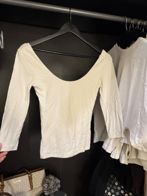 Vit trekvartsärmad topp  - Säljer en enkel och stilren vit topp från Gina Tricot i storlek XS. Toppen är trekvartsärmad och har en djup, rundad ringning både fram och bak. Tillverkad i mjuk bomullsmix som känns skön mot huden. Perfekt att matcha med jeans eller kjol.