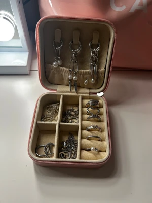 Rosa smyckeskrin med dragkedja - Snyggt smyckesskrin i ljusrosa med dragkedja. Perfekt för att organisera ringar, örhängen och halsband. Enkel att ta med på resa och smyckena slipper trassla ihop sig! Om ni är intresserade av att köpa några ringar, skriv till mig (typ alla är till salu)