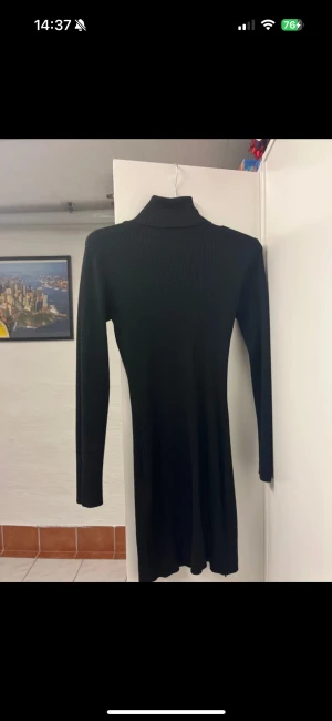 Svart ribbad poloklänning - Säljer en svart, ribbad klänning med polokrage och lång ärm. Klänningen har en slim passform och är tillverkad i ett stickat material som sitter snyggt mot kroppen. Perfekt för dig som gillar minimalistisk och stilren look. Superfin till nyår.