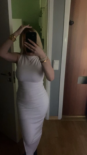 Vit långklänning med ärmlös design - Säljer en stilren vit långklänning med ärmlös och figurnära passform. Klänningen har rund halsringning och slät yta utan mönster eller detaljer. Perfekt för dig som gillar minimalistisk och elegant stil.