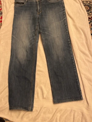 Blå raka jeans  - Snygga blå jeans från Levi's med klassisk rak passform och fem fickor. Jeansen har en lätt tvättad look och är tillverkade i slitstarkt denim. Perfekta för dig som gillar en enkel och tidlös stil.