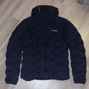 Blå dunjacka från Stellar Equipment - Säljer en blå dunjacka från Stellar Equipment, modell Stretch Down Hood 2.0. Originalpris är 3500kr. Har använt den runt 5 gånger.